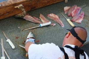 man filleting fish with knife