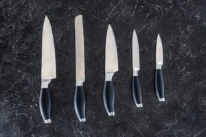 five knives lined up on black background