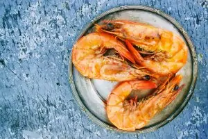 three shrimp on white plate on marble counter
