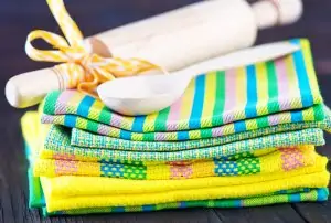 stack of pastel dish towels with white spoon rest on top against black background