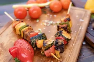 grilled kebabs on wooden cutting board with tomatoes