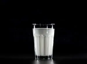 glass of buttermilk made from almond milk against black background