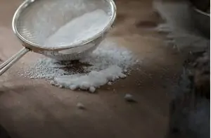 sifter with flour on wooden cutting board