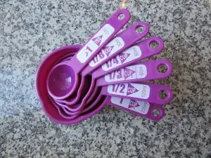 purple nested measuring cups and spoons on granite countertop