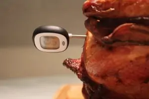 black and gray digital thermometer stuck in side of cooked turkey