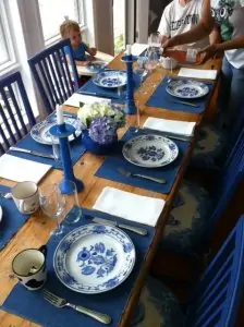 blue and white china on wood table set with blue candles and blue chairs