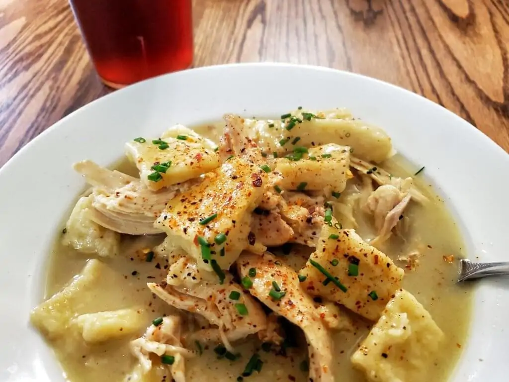 white bowl on table with chicken and dumplings