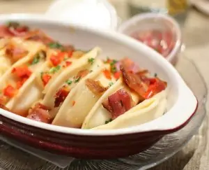 white casserole dish with perogies and vegetables