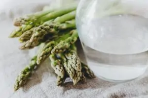 asparagus next to glass of water with a bit of water in bottom