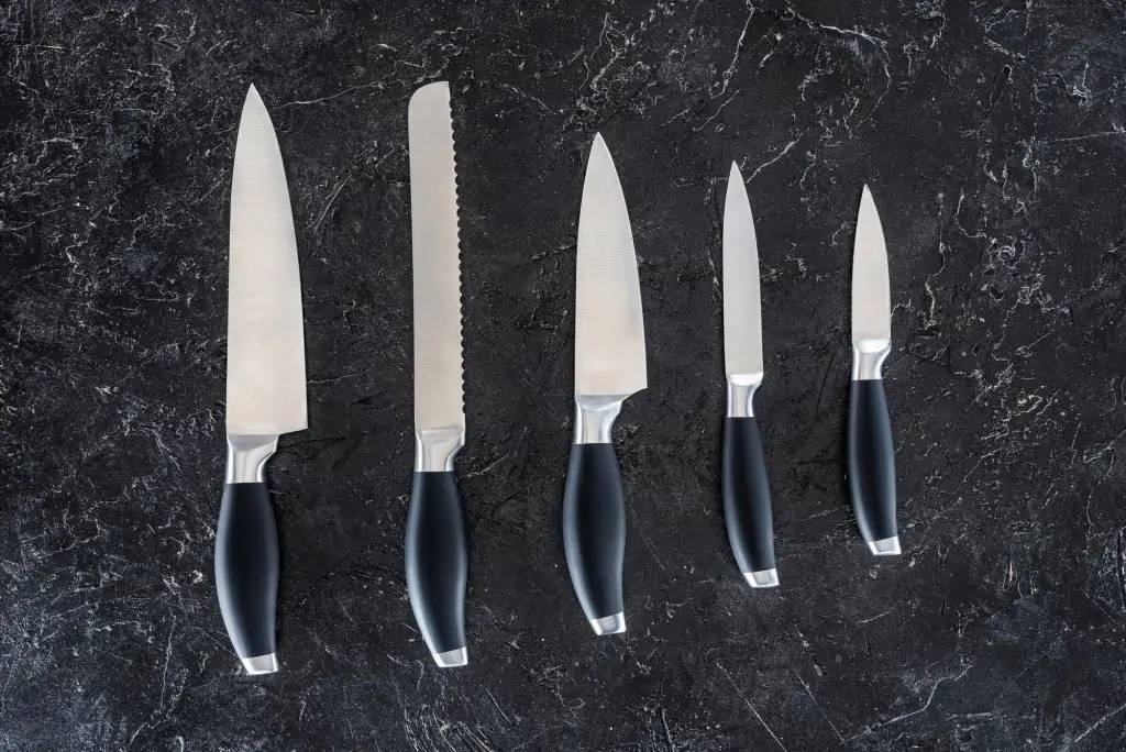 five knives lined up on black counter in order of sizes