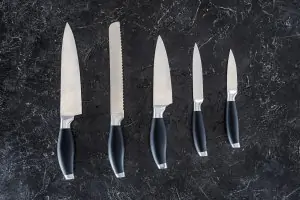 five knives lined up in order of size on black countertop