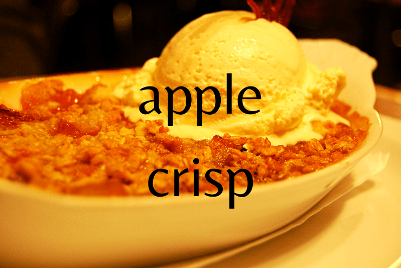 apple crisp with scoop of vanilla ice cream in oval white bowl