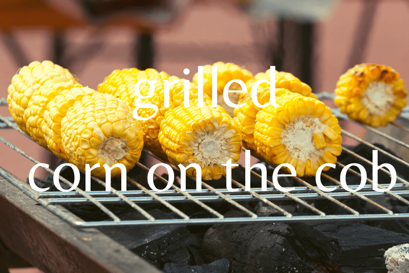 corn on the cob being grilled over charcoal grill
