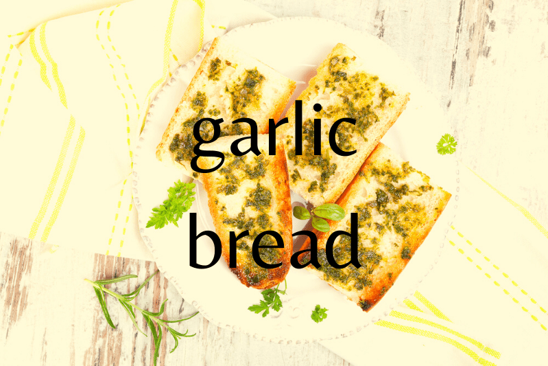 white plate on wooden table with four slices of garlic bread with parsley