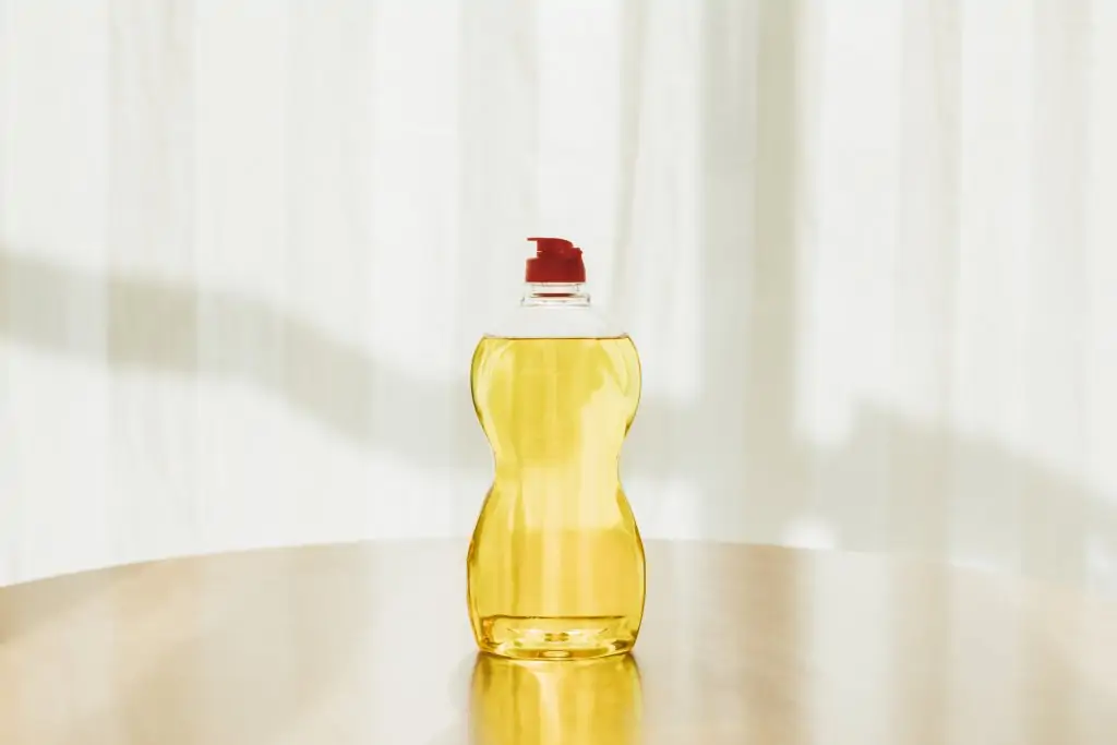 yellow dish soap in plastic bottle against white background