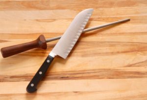 chef's knife and honing rod on wooden board