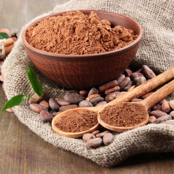 cocoa powder in a bowl next to some cocao beans