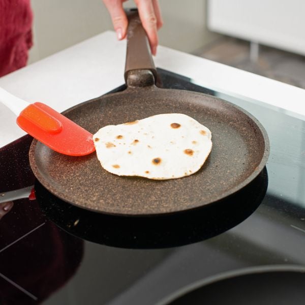 Someone heating tortilla on a non-stick pan