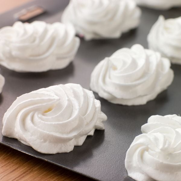 piped meringues on a dark tray