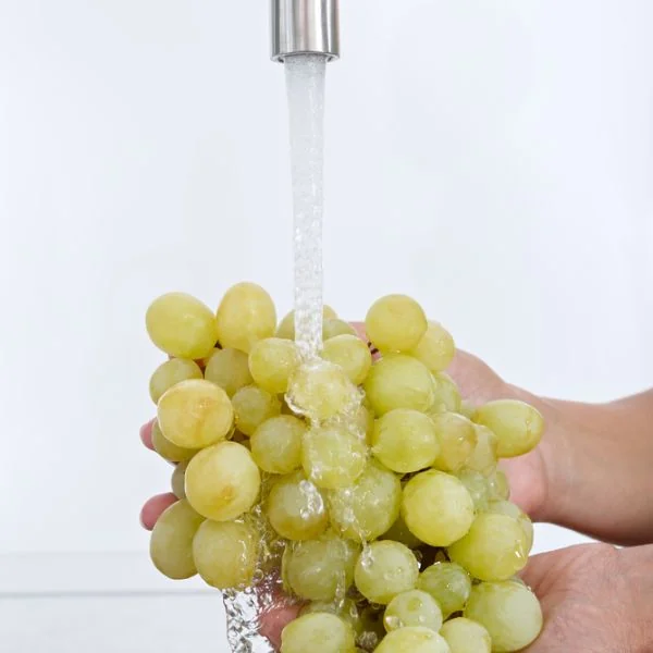someone washing grapes