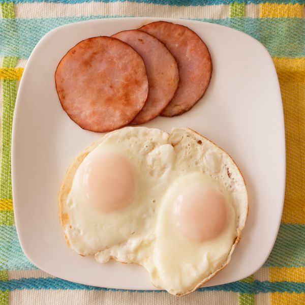 steam basted eggs on a plate with canadian bacon