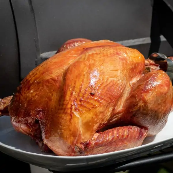 Smoked whole turkey on a white plate on a grill