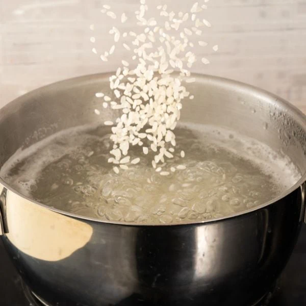 Short-grained rice being put into a boiling pot of water
