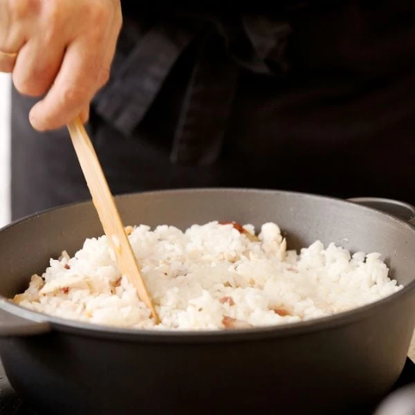 Someone stirring rice in an oven-safe bowl