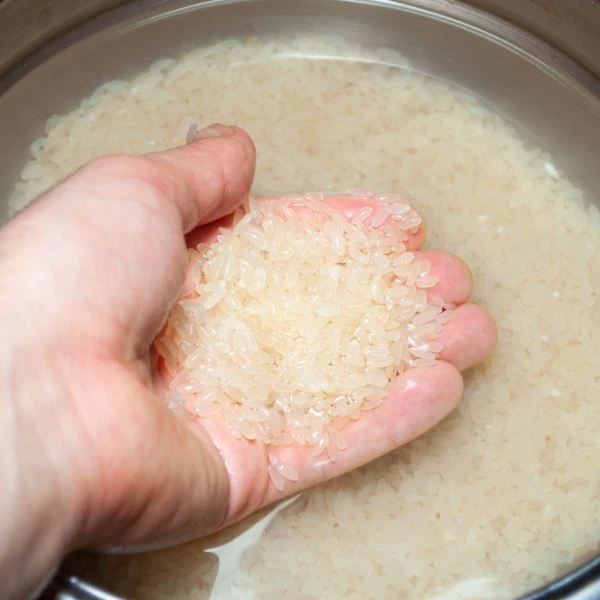 Someone putting their hand through rice in water