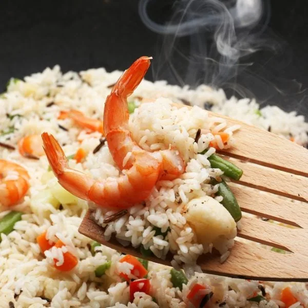 Stir-frying rice with ingredients in wok