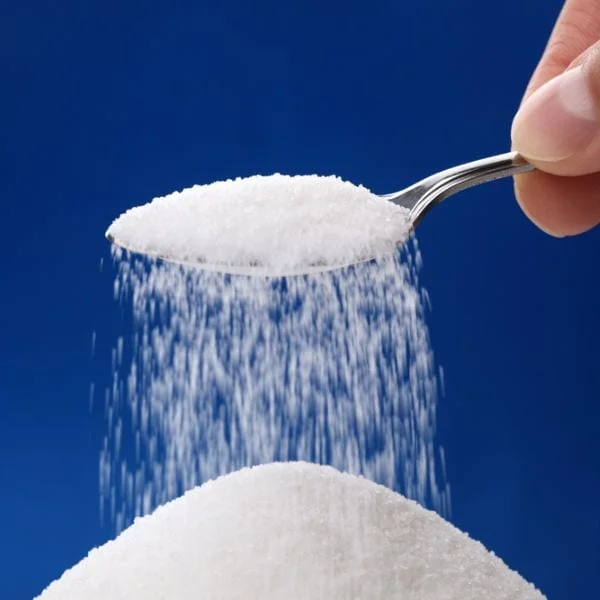 White sugar being poured in front of a blue background