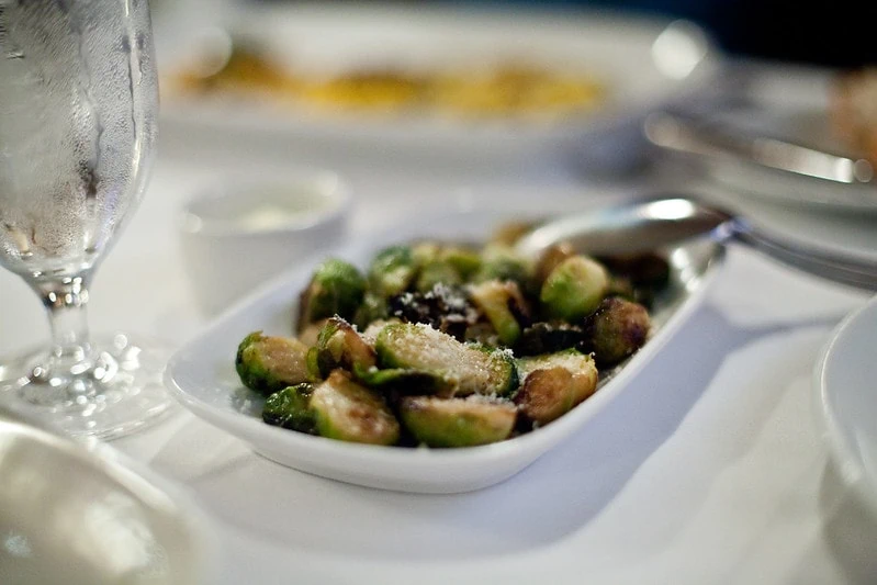 Brussel sprouts with chorizo on a white plate