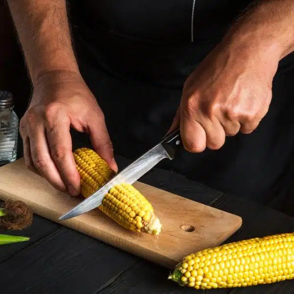 Corn being cut to be served as a dish