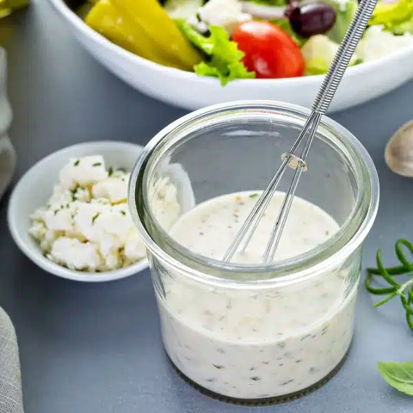 Homemade ranch dressing next to a plate of salad