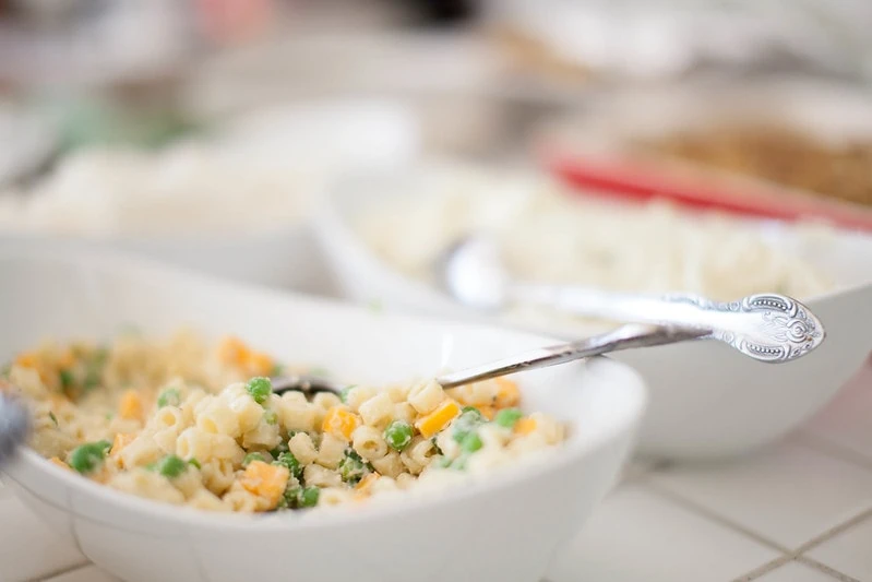 Macaroni and cheese salad with a silver spoon in a white bowl