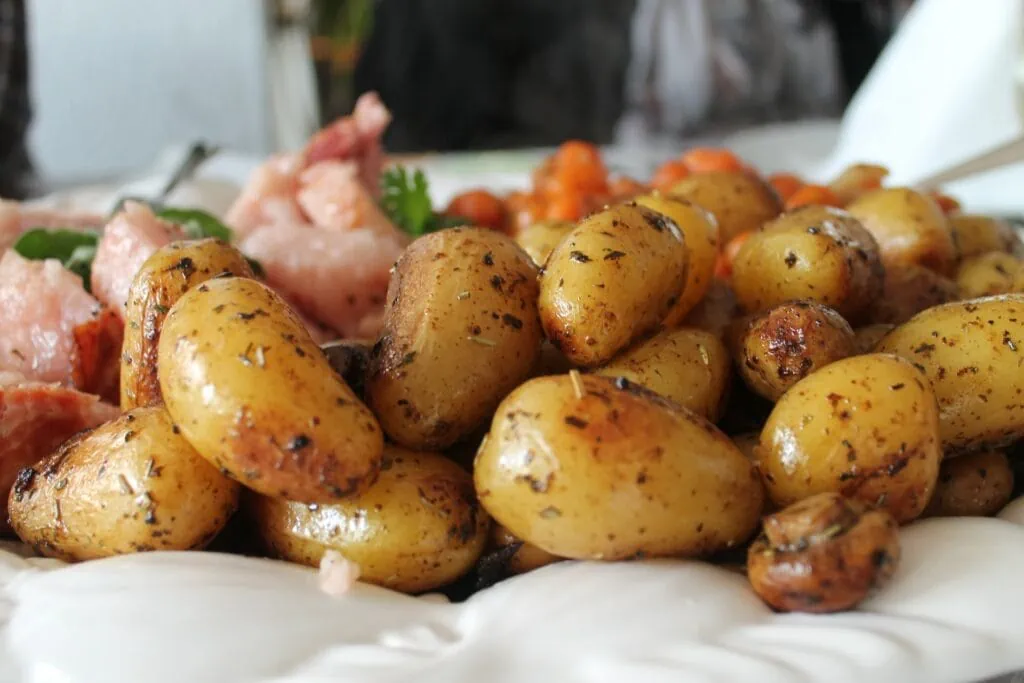 Oven roasted potatoes in front of chicken and carrots on a white cloth