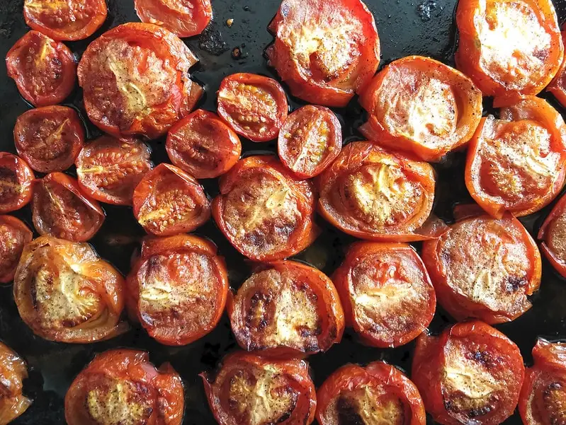 Roasted tomatoes sitting on a black table