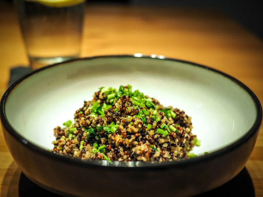 Seasoned quinoa in a black bowl on a wooden table