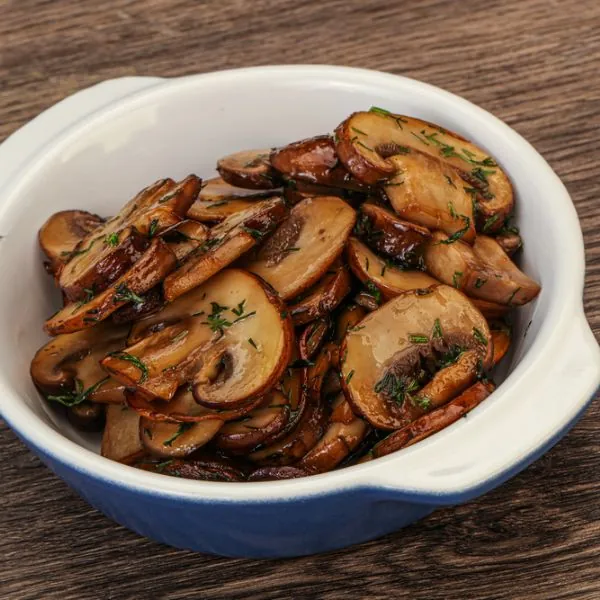 Simple sautéed mushrooms and onions in a bowl garnished with herbs