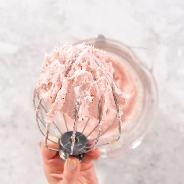 Strawberry buttercream being whipped by a whisk