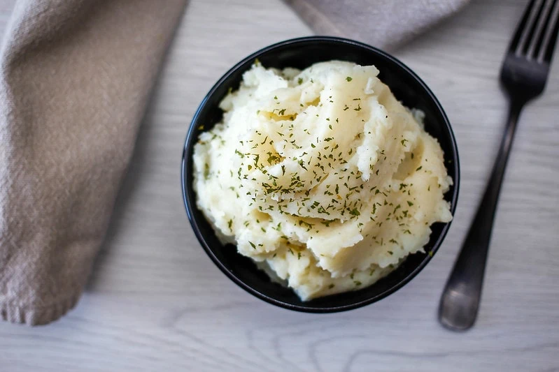 Mashed potatoes in a black bowl sitting next to a fork