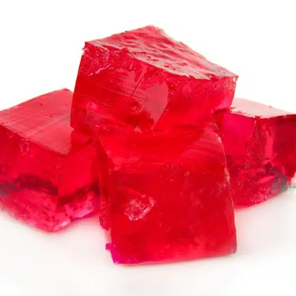 Four cubes of red jello on a white background