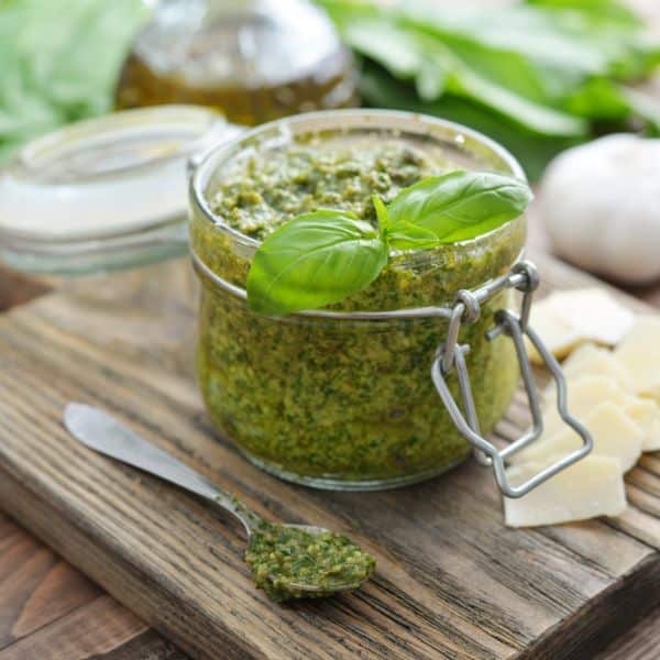 Homemade pesto in a glass jar on a wooden board